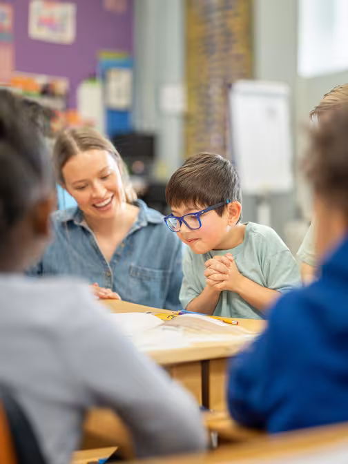 Eine Schulbegleiterin motiviert einen Jungen im Unterricht.